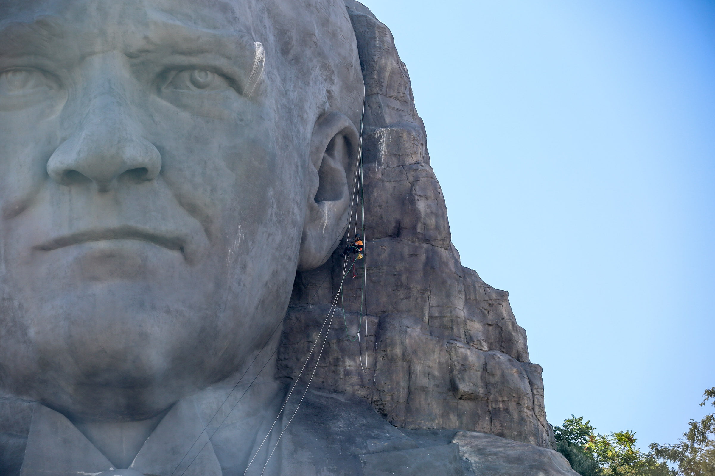 atatürk maskı En Büyük Atatürk Maskı Bakıma Alındı
Buca Belediyesi, Türkiye’nin en büyük, en ihtişamlı Atatürk maskını bakıma aldı. Buca’nın Yeşildere sırtlarından tüm İzmir’i kucaklayan Atatürk maskının güneş ve kuşlar nedeniyle
kirlenen bölgeleri özel dağcılık ekibince temizlendi.
Buca’nın hatta İzmir’in simgeleri arasında yer alan Türkiye’nin en büyük, dünyanınsa 10’uncu büyük rölyef maskı olan Atatürk maskı, Buca Belediyesi tarafından bakıma alındı. Çaldıran
mahallesi çevre yolu güzergahına bakan kayalıklarda konumlanan maskın bakım ve temizlik işlemleri için profesyonel dağcılık ekibinden destek alındı.
Maskın çeşitli bölgelerine iplerle inen dağcılar, ilk olarak inceleme ve tespit çalışması yaptı. Konum itibari ile yoğun güneş, rüzgar ve yağışa maruz kalan maskın yüzeyindeki hasarlar kontrol edilerek raporlandı. İnceleme sonucunda bölgede yaşanan yoğun kuş trafiği nedeniyle maskın kaş ve kulak bölgelerinde yuvalar tespit edildi. 42 metrelik dev maskın bazı bölgelerinde aşırı sıcaklar nedeniyle oluşan yıpranmalar ve yırtıcı kuşların yiyecek artıkları ve neden olduğu kirlenme özel kimyasallarla temizlendi. Yürütülen çalışmada kuşlara zarar verilmemesine dikkat edildi.