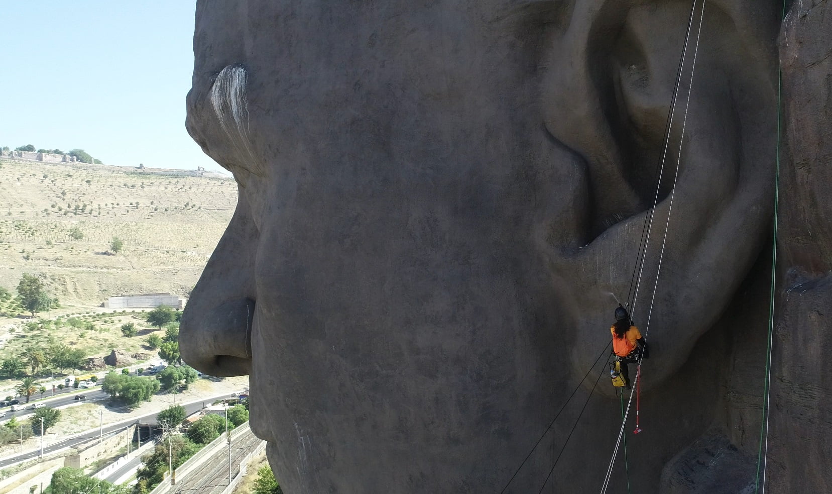 atatürk maskı En Büyük Atatürk Maskı Bakıma Alındı
Buca Belediyesi, Türkiye’nin en büyük, en ihtişamlı Atatürk maskını bakıma aldı. Buca’nın Yeşildere sırtlarından tüm İzmir’i kucaklayan Atatürk maskının güneş ve kuşlar nedeniyle
kirlenen bölgeleri özel dağcılık ekibince temizlendi.
Buca’nın hatta İzmir’in simgeleri arasında yer alan Türkiye’nin en büyük, dünyanınsa 10’uncu büyük rölyef maskı olan Atatürk maskı, Buca Belediyesi tarafından bakıma alındı. Çaldıran
mahallesi çevre yolu güzergahına bakan kayalıklarda konumlanan maskın bakım ve temizlik işlemleri için profesyonel dağcılık ekibinden destek alındı.
Maskın çeşitli bölgelerine iplerle inen dağcılar, ilk olarak inceleme ve tespit çalışması yaptı. Konum itibari ile yoğun güneş, rüzgar ve yağışa maruz kalan maskın yüzeyindeki hasarlar kontrol edilerek raporlandı. İnceleme sonucunda bölgede yaşanan yoğun kuş trafiği nedeniyle maskın kaş ve kulak bölgelerinde yuvalar tespit edildi. 42 metrelik dev maskın bazı bölgelerinde aşırı sıcaklar nedeniyle oluşan yıpranmalar ve yırtıcı kuşların yiyecek artıkları ve neden olduğu kirlenme özel kimyasallarla temizlendi. Yürütülen çalışmada kuşlara zarar verilmemesine dikkat edildi.